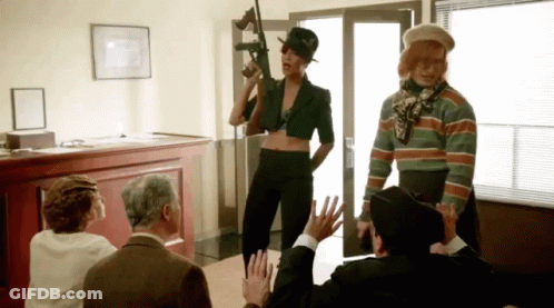 A Woman Holding A Gun Is Surrounded By People GIF