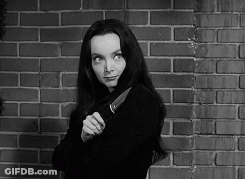 A Woman Holding A Large Knife In Front Of A Brick Wall GIF