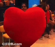 A Woman Holding A Large Red Heart Pillow GIF
