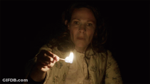 A Woman Holding A Lit Match In Her Hand GIF