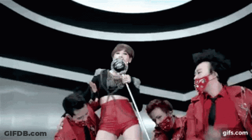 A Woman Holding A Lollipop Is Surrounded By A Group Of Men In Red GIF