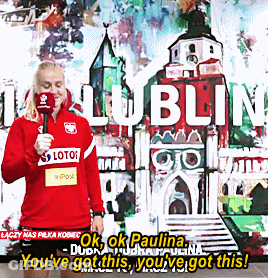 A Woman Holding A Microphone Standing In Front Of A Wall That Says Lublin GIF