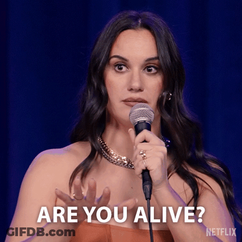 A Woman Holding A Microphone With The Words Are You Alive Behind Her GIF