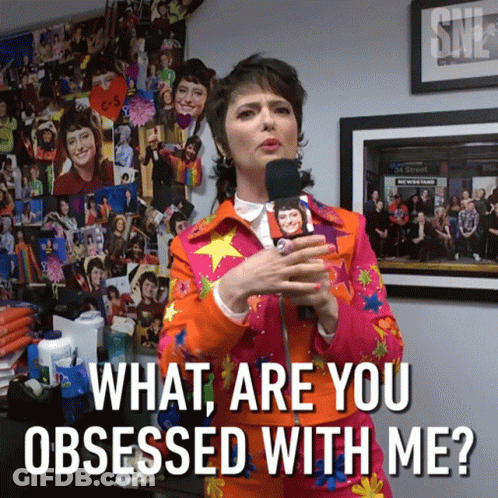 A Woman Holding A Microphone With The Words What Are You Obsessed With Me Below Her GIF