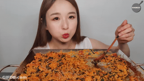 A Woman Holding A Spoon In Front Of A Pan Of Food With The Word Hamzy On The Bottom GIF