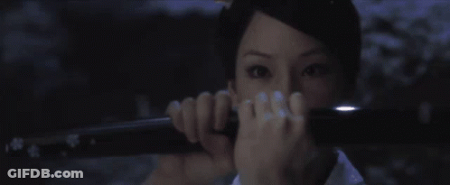 A Woman Holding A Sword In Front Of Her Face GIF