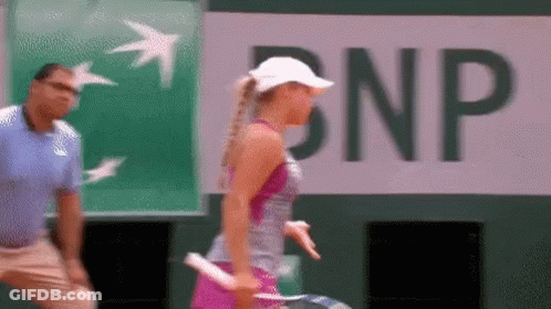 A Woman Holding A Tennis Racquet In Front Of A Bnp Banner GIF