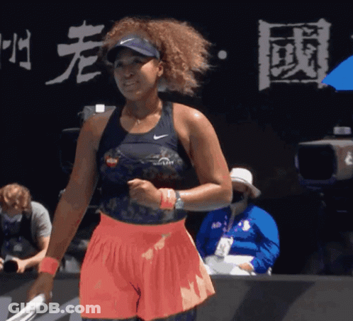 A Woman Holding A Tennis Racquet In Front Of A Sign That Has Chinese Writing On It GIF