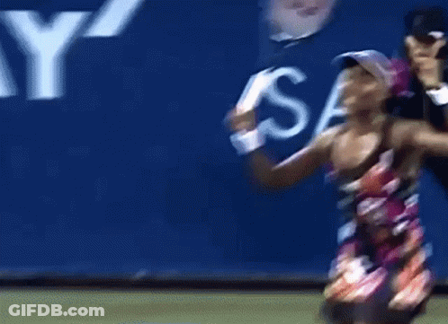 A Woman Holding A Tennis Racquet In Front Of A Sign That Says S. GIF