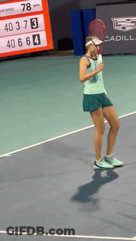 A Woman Holding A Tennis Racquet On A Court With A Cadillac Sign In The Background GIF