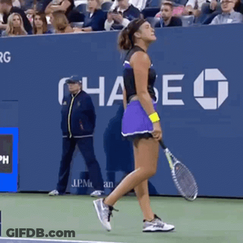 A Woman Holding A Tennis Racquet On A Tennis Court With Chase In The Background GIF