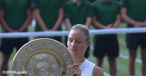 A Woman Holding A Trophy In Front Of A Crowd Of People GIF