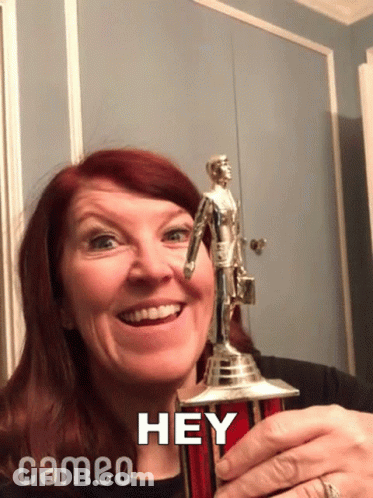 A Woman Holding A Trophy That Says Hey Cameo On The Bottom GIF