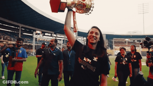 A Woman Holding A Trophy That Says Wpi Champions On It GIF