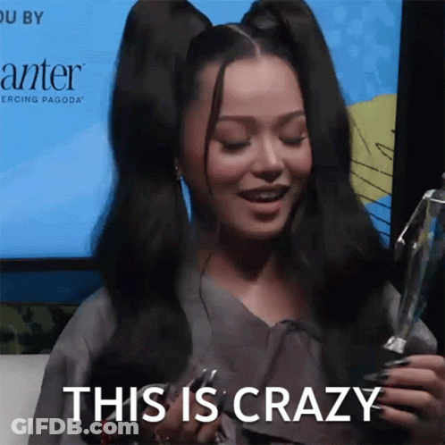 A Woman Holding A Trophy With The Words This Is Crazy Behind Her GIF