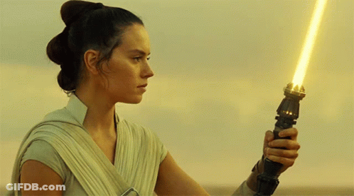 A Woman Holding A Yellow Light Saber In Her Hand GIF