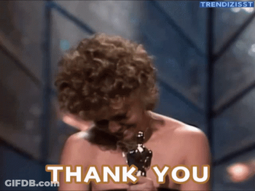 A Woman Holding An Oscar Statue With The Words Thank You Behind Her GIF