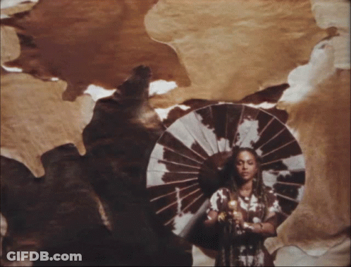 A Woman Holding An Umbrella In Front Of A Brown And White Cowhide GIF