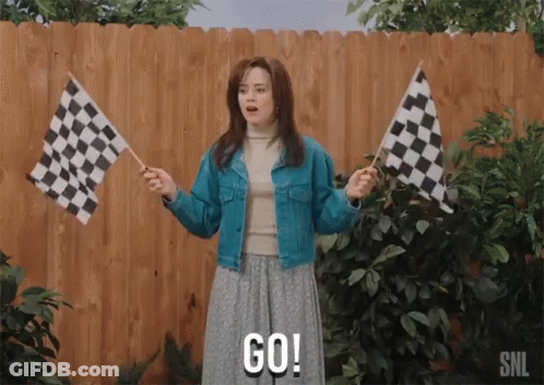 A Woman Holding Two Checkered Flags And Says Go GIF