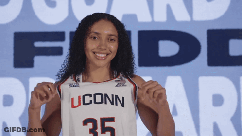 A Woman Holding Up A Uconn Jersey With The Number 35 GIF