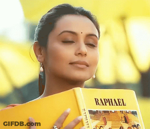 A Woman Holds A Book Titled Raphael In Her Hands GIF