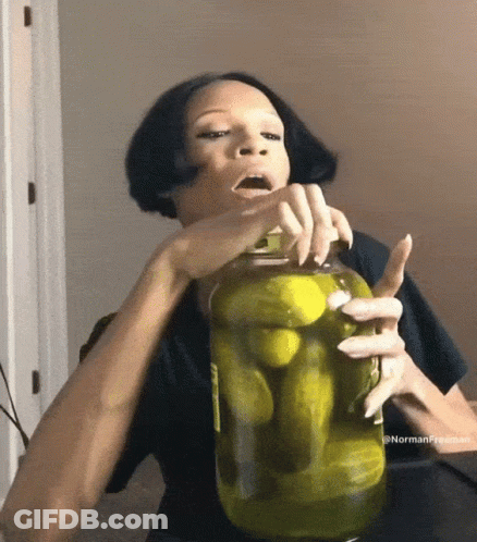 A Woman Holds A Jar Of Pickles In Her Hand GIF
