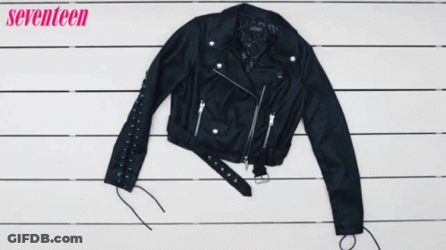 A Woman Holds A Pair Of Black Boots Next To A Plaid Shirt And A Leather Jacket GIF