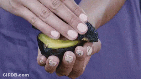 A Woman Holds A Sliced Avocado In Her Hand GIF