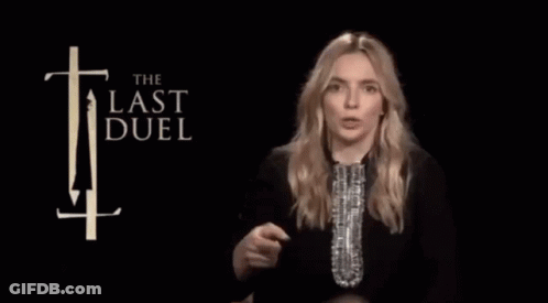A Woman Holds A Trophy In Front Of A Sign That Says The Last Duel GIF