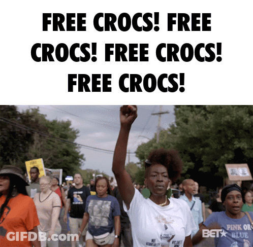 A Woman Holds Her Fist In The Air In Front Of A Sign That Says " Free Crocs " GIF