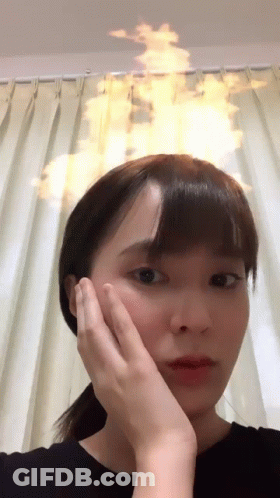 A Woman Holds Her Hand To Her Face With A Fire Coming Out Of Her Head GIF