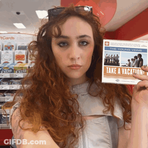 A Woman Holds Up A Cd Titled Take A Vacation GIF