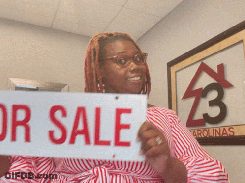 A Woman Holds Up A For Sale Sign GIF