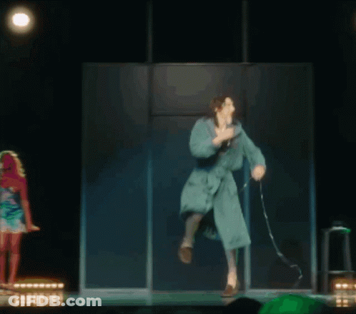 A Woman In A Bathrobe Is Dancing On A Stage GIF