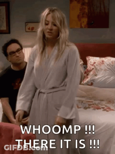 A Woman In A Bathrobe Is Standing In Front Of A Bed And Says Whoomp There It Is GIF