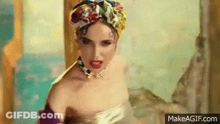 A Woman In A Bathtub Wearing A Turban And A Necklace Is Making A Funny Face . GIF