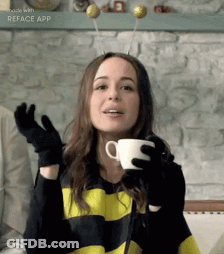 A Woman In A Bee Costume Is Holding A Cup Of Coffee In Her Hands . GIF