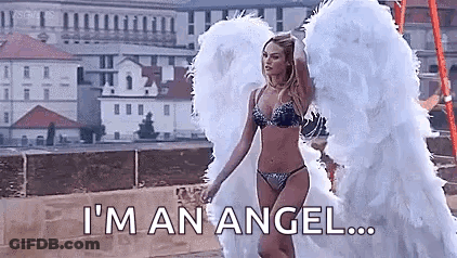 A Woman In A Bikini And Angel Wings Is Standing On A Bridge . GIF