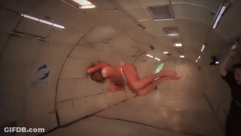 A Woman In A Bikini Is Floating In A Room With The Word Zero G On The Wall GIF