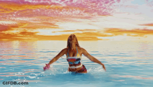 A Woman In A Bikini Is In The Water With Her Arms In The Air And A Shirt That Says Beach House GIF