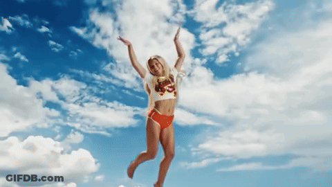 A Woman In A Bikini Is Jumping In The Air With Her Arms Outstretched GIF