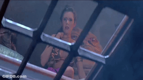 A Woman In A Bikini Is Sitting On A Bed Behind A Fence . GIF