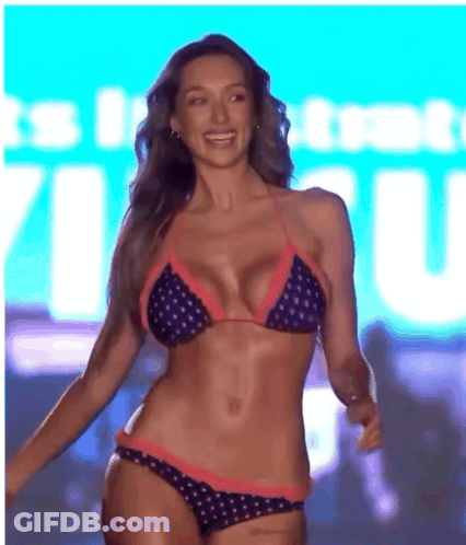 A Woman In A Bikini Is Smiling In Front Of A Sign That Says ' It 'S In ' GIF