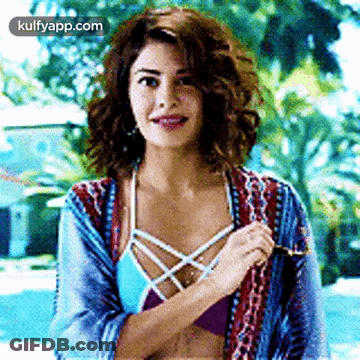 A Woman In A Bikini Is Standing In Front Of A Pool . GIF