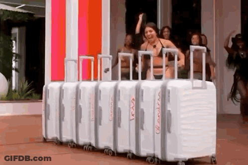 A Woman In A Bikini Is Standing In Front Of A Row Of White Suitcases . GIF