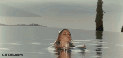A Woman In A Bikini Is Standing In The Water . GIF