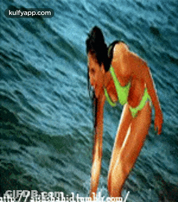 A Woman In A Bikini Is Standing In The Water And The Website Is Kulfyapp.com GIF