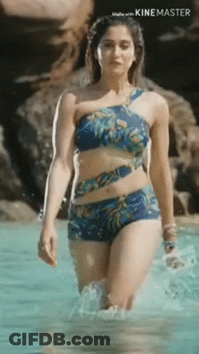 A Woman In A Bikini Is Walking Out Of A Pool . GIF