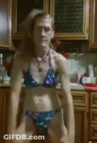 A Woman In A Bikini Sits On A Counter In A Kitchen GIF