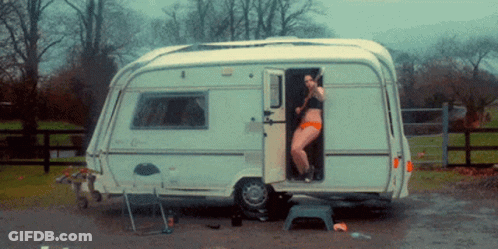 A Woman In A Bikini Stands In The Doorway Of A Camper GIF